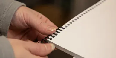 A hand holding a spiral-bound document.