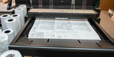 A large-format plotter printing a building plan.